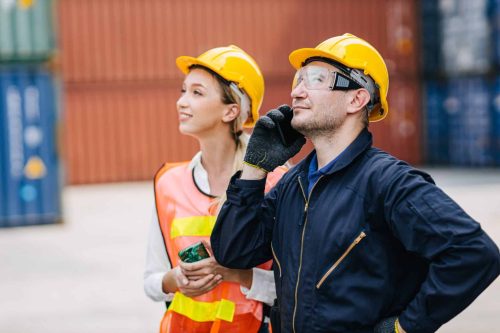 logistic worker teamwork working using smartphone calling command order control loading containers at port cargo to trucks for export and import goods.